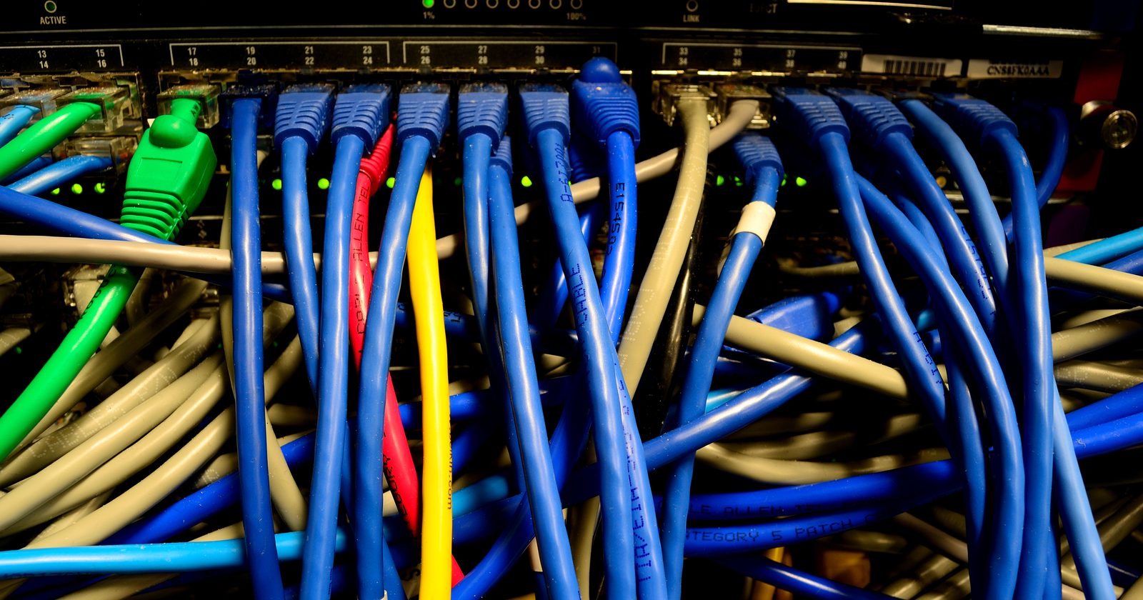 Plątanina kolorowych kabli sieciowych wpiętych w przełącznik ethernetowy
